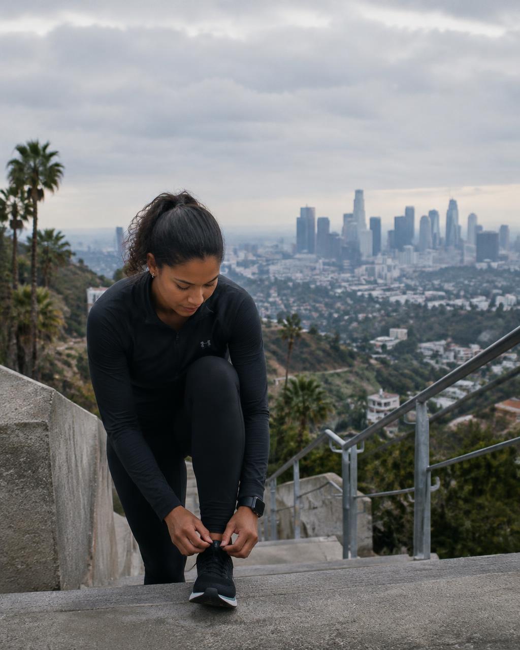 Runner tying her shoes above the Los Angeles skyline
